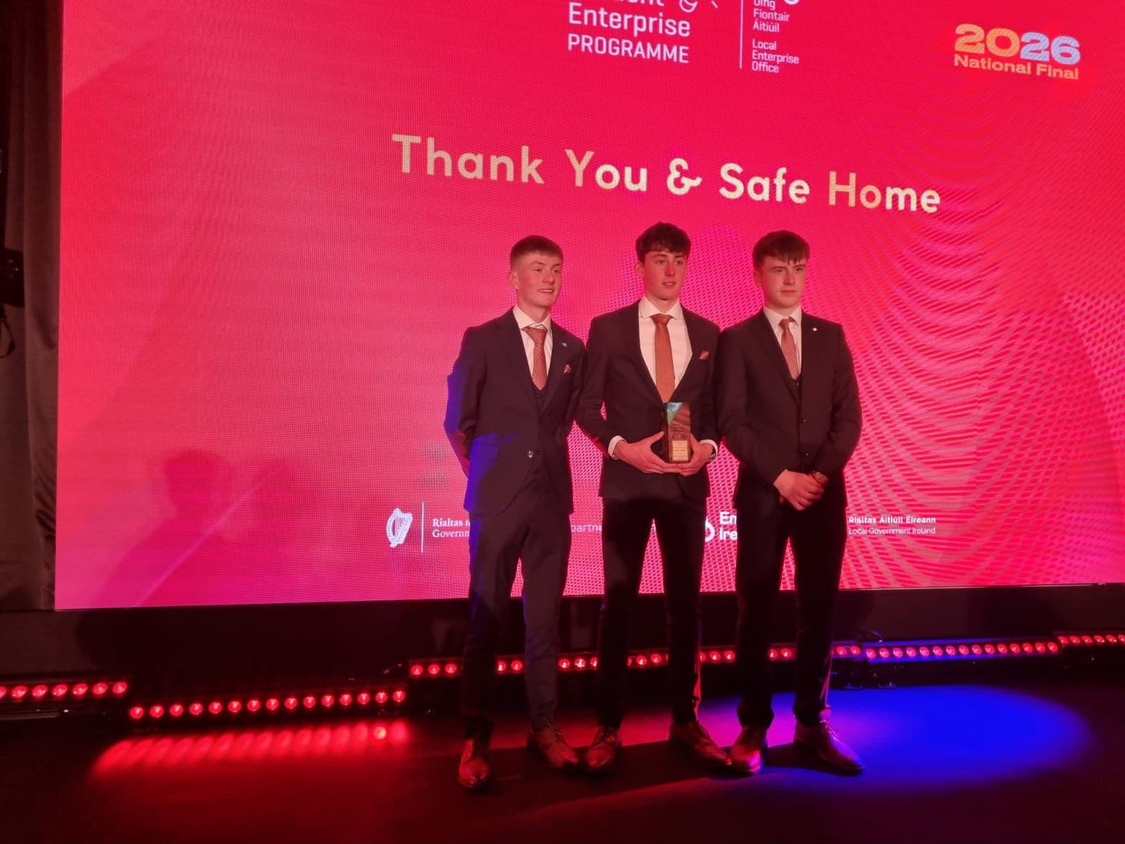 Three students on stage holding an award at the 2026 Student Enterprise Programme National Final